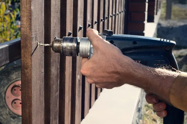Golden Locks, Inc. technician diagnosing a jammed gate lock on a wrought iron fence gate in Huntington Beach CA
