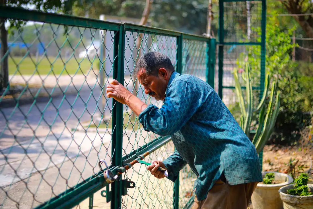 Worker repairing the lock on a metal gate