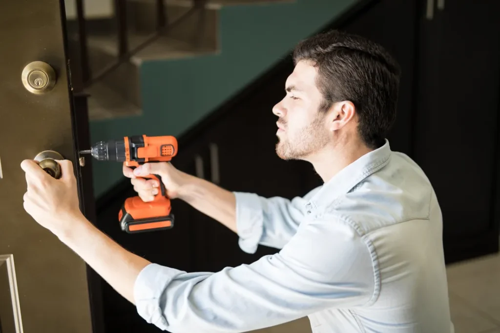 Locksmith installing a door knob with a power drill