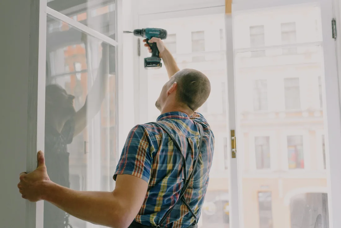 Technician repairing a sliding door frame with a power drill