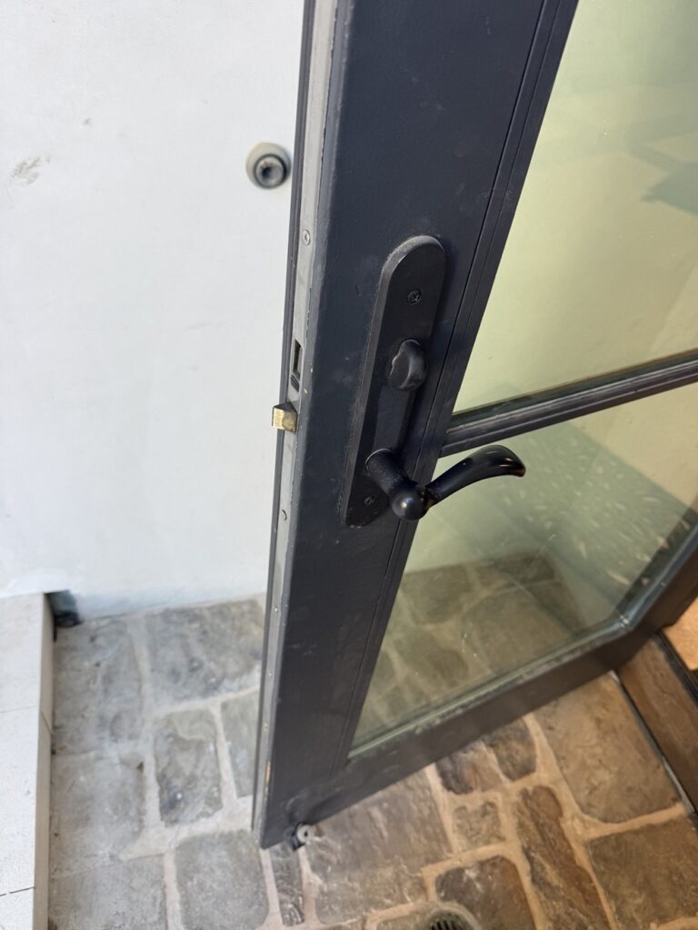Black lever and multipoint lock hardware on an aluminum-framed patio door