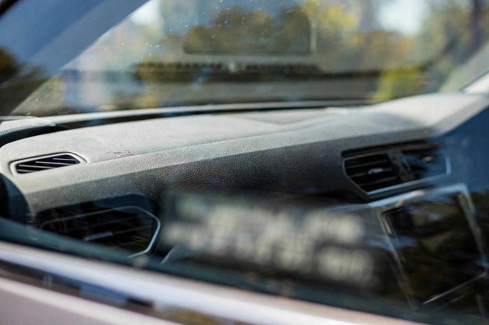 Can a Locksmith Make a BMW Key? What You Need and How Long It Takes in Huntington Beach View through a car windshield of the dashboard corner where the VIN plate sits, with the number blurred